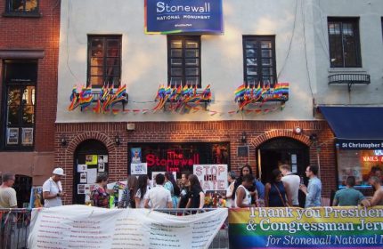 The Stonewall Inn in New York, a gay bar and historic landmark, is decorated with rainbow flags. People gather outside the Stonewall National Monument.