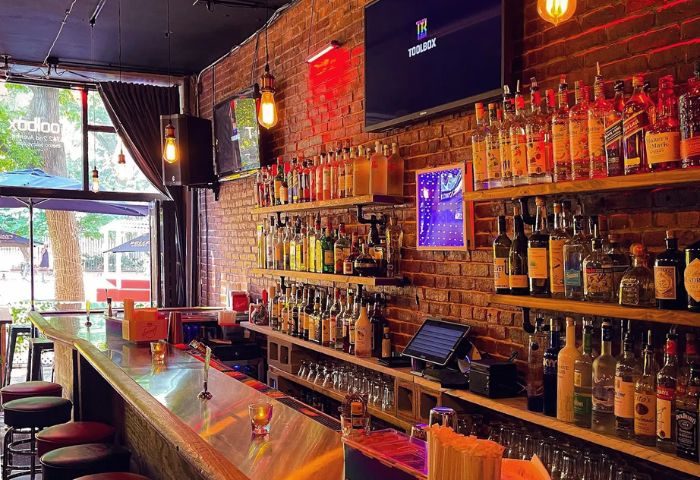 The ToolBox Bar in New York: Interior shot of a popular gay bar. Brick walls, liquor shelves, and a long bar with stools. Great gay travel spot.