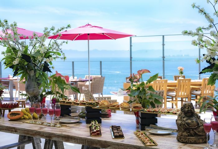 Puerto Vallarta's Top Sky Gay Bar: Buffet with ocean view. Pink umbrellas, flowers, and a Buddha statue decorate the table.