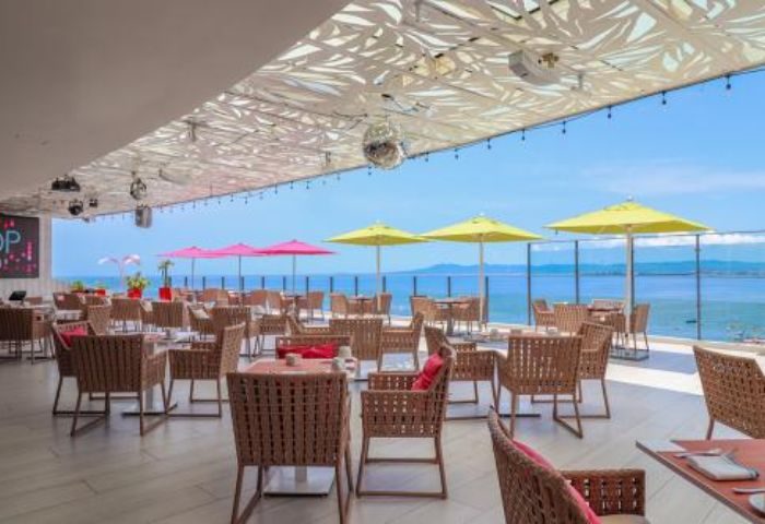 The Top sky gay bar in Puerto Vallarta. Rooftop seating with ocean views, umbrellas, tables, and chairs. Gay travel destination.