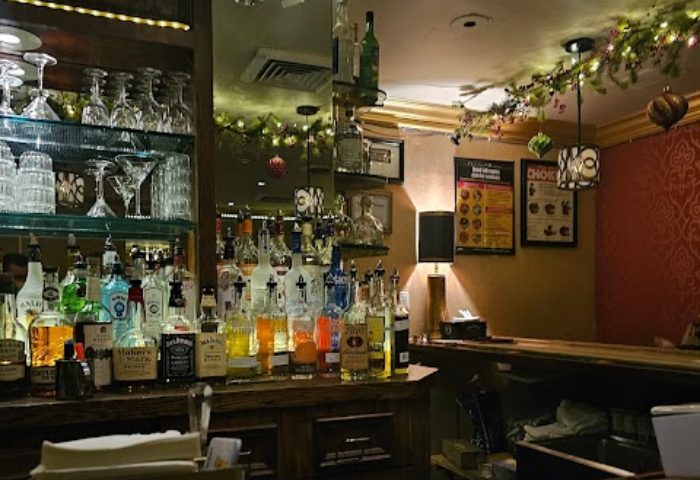 The Townhouse Bar in New York: Bottles of liquor line the bar's surface, with glassware above. Holiday decorations add festive cheer. Gay bar.