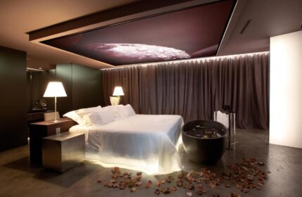 The Vine Hotel, a gay-friendly hotel in Madeira. Luxury suite with bed, bathtub, and leaf decorations. Upscale gay travel experience.