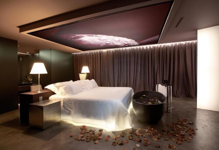 The Vine Hotel, a gay-friendly hotel in Madeira. Luxury suite with bed, bathtub, and leaf decorations. Upscale gay travel experience.