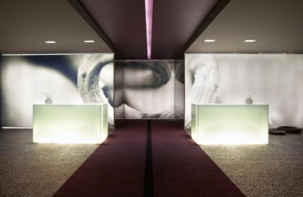 The Vine Hotel lobby. Gay-friendly hotel with modern design, illuminated desks, and a purple carpet. Stylish and welcoming space.