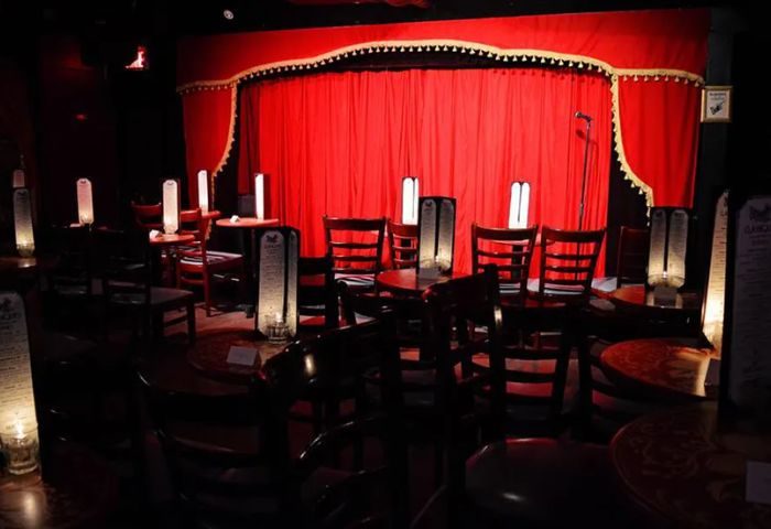 Interior of The Wiggle Room gay bar in Montreal, Canada. Red stage curtain, tables, chairs, and soft lighting create a cozy ambiance. Live show venue.
