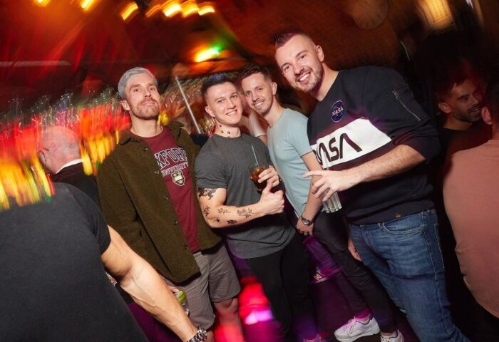 Gay men at The Yard Bar, a cool gay bar in London's Soho. The Yard has an outdoor garden bar. Nightlife scene, drinks, socializing.