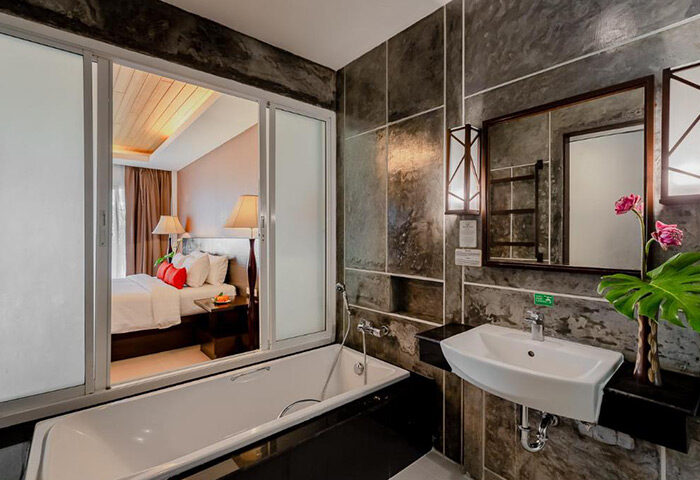 Railay Princess Resort & Spa bathroom. Krabi gay hotel's budget room interior: bathtub, sink, mirror, and bedroom view.