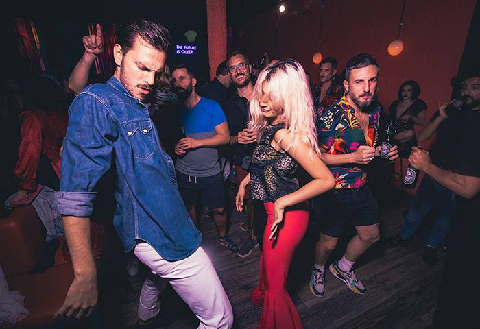 Gay nightlife Barcelona: People dancing at a gay bar. Energetic scene with diverse outfits, capturing the vibrant atmosphere of Barcelona's gay scene.