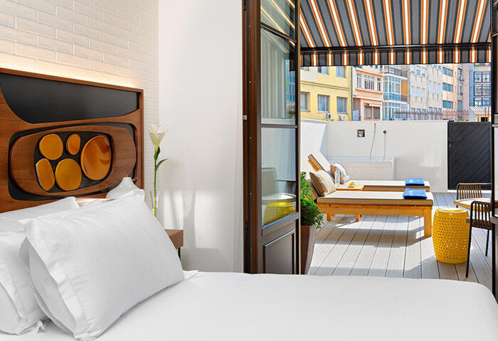 H10 Metropolitan Hotel room in Barcelona's Eixample. Balcony view with sun loungers. Gay-friendly hotel with modern design and city views.