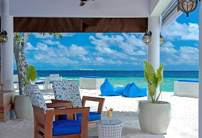 Beachfront view from Malahini Kuda Bandos Resort, Maldives. Gay-friendly hotel with blue cushions, beanbags, white sand, and ocean views.