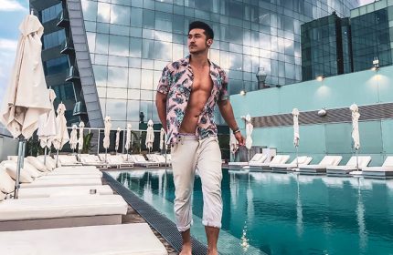W Barcelona gay hotel infinity pool. Man in floral shirt at luxury hotel pool. Best gay travel destination in Barcelona.