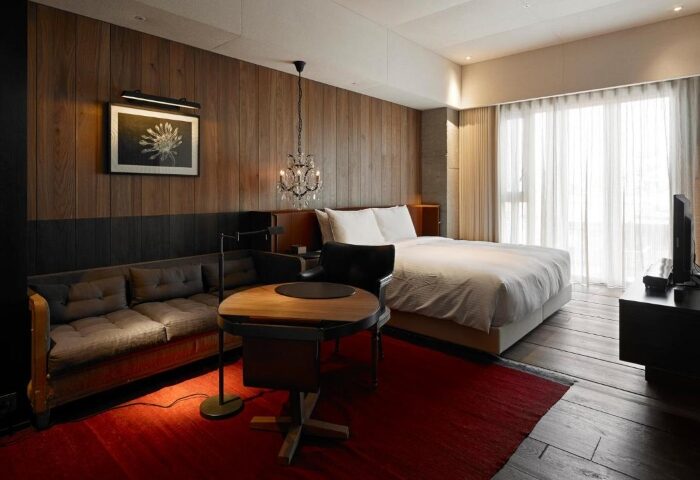Hotel Proverbs Taipei room. Gay Pride hotel list update. Wood paneled wall, sofa, table, bed, and chandelier. Gay travel advice.