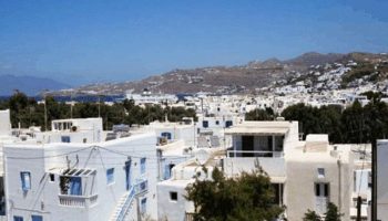 Mykonos Town view: White buildings, blue accents. Gay travel in Mykonos. 3-star hotels for gay men. M for Mykonos travel guide.