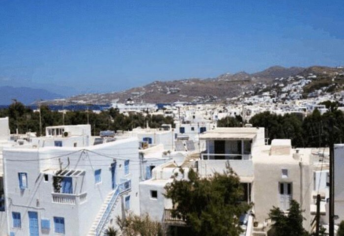 Mykonos Town view: White buildings, blue accents. Gay travel in Mykonos. 3-star hotels for gay men. M for Mykonos travel guide.
