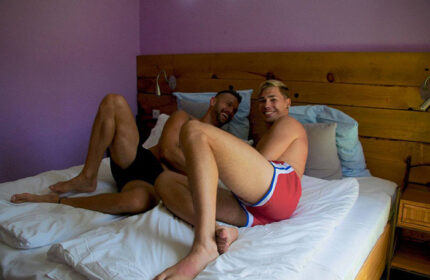 Two men relaxing in bed at Paso Chico Gay Hotel, Gran Canaria. Best budget gay hotel with pool for gay travel.