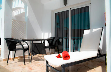 Vista Bonita Gay Only Resort balcony. Maspalomas gay hotel with chairs, table, and lounger. Budget-friendly gay travel in Gran Canaria.