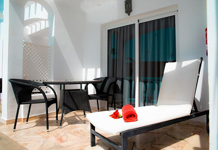 Vista Bonita Gay Only Resort balcony. Maspalomas gay hotel with chairs, table, and lounger. Budget-friendly gay travel in Gran Canaria.