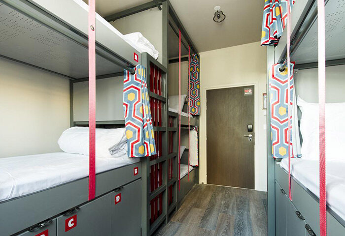 Dorm room at Les Piaules, a clean hostel in Paris' Gayborhood. Bunk beds with privacy curtains, lockers underneath. Great for gay travelers.