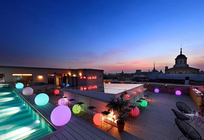 Axel Hotel Madrid rooftop pool at dusk. This adults-only gay hotel features colorful glowing orbs, a bar, and city views. Best gay hotel.