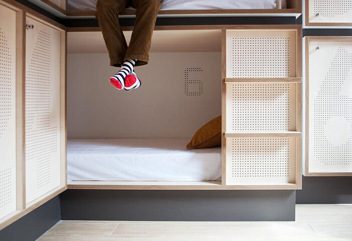 TOC Hostel Barcelona bunk bed. Best gay hostel Barcelona. Man with socks sitting on top bunk. Modern hostel design.
