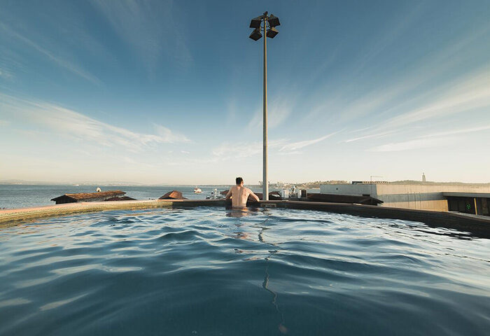Gay traveler at Sunset Destination Hostel rooftop pool in Lisbon. Best gay hostel with sunset views. Gay travel advice.