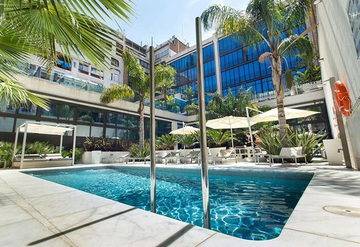 Hotel Indigo Barcelona Plaza Catalunya pool area. Best gay hotel in Barcelona with pool. Sunbeds and parasols for relaxing. Palm trees.