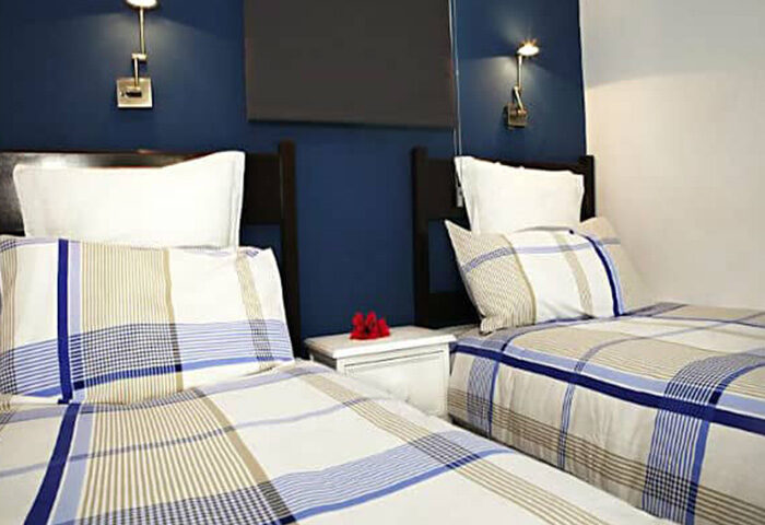 Bungalows Tenesoya, a gay men-only hotel in Playa del Ingles, Gran Canaria. Twin beds with plaid bedding in a modern room. Gay travel.