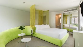 Room Mate Oscar Hotel in Madrid, a top gay hotel. Modern room with green decor, white bed, and stylish design. Best hotel in Madrid city center.