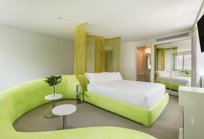 Room Mate Oscar Hotel in Madrid, a top gay hotel. Modern room with green decor, white bed, and stylish design. Best hotel in Madrid city center.