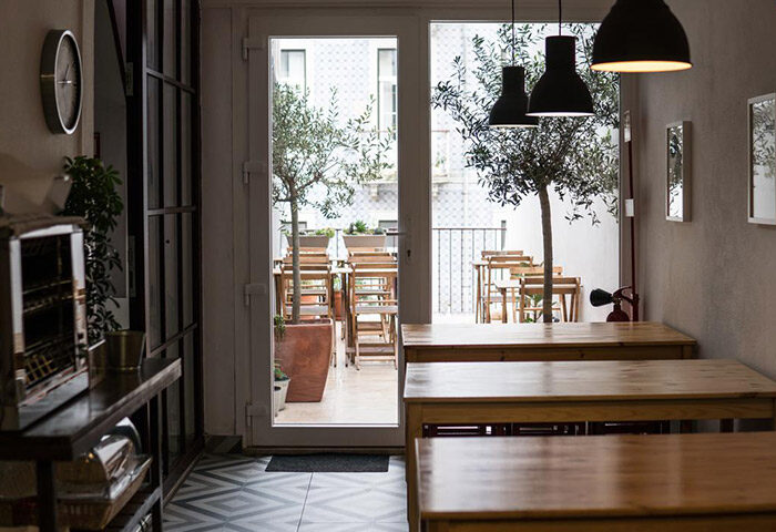 Lisbon Poets Inn Hostel interior. City Center gay hostel with tables, lamps, and a view to an outdoor patio with olive trees.