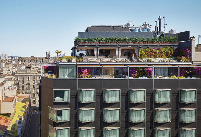 The Barcelona EDITION hotel's rooftop bar and city view. Luxury gay honeymoon hotel in city center with floral decor and modern architecture.