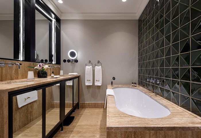 Bairro Alto Hotel's luxury bathroom in Lisbon city center. Features a soaking tub, double vanity, and modern design. Best gay hotel update.