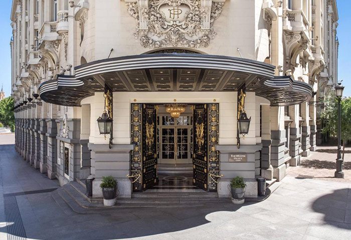 The Westin Palace Madrid entrance. Luxury gay-friendly hotel in Madrid. Ornate gold and black doors, elegant architecture.