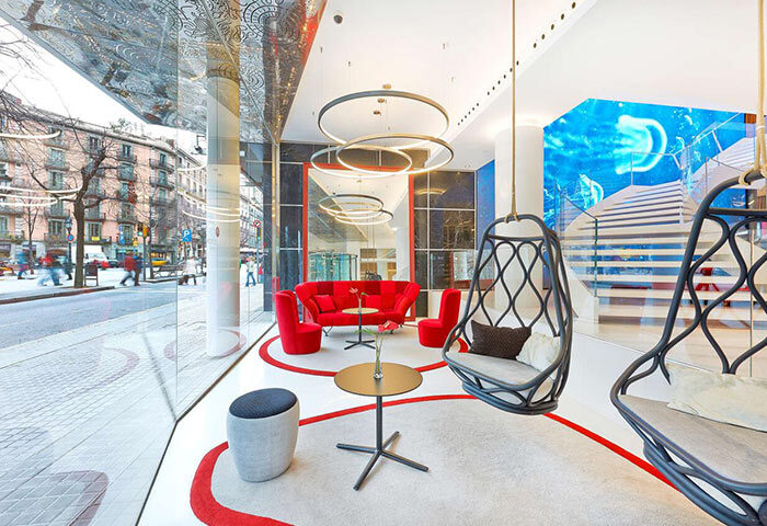 NH Collection Barcelona Gran Hotel Calderon lobby. Luxury gay hotel in Barcelona city center with stylish seating, red accents, and modern design.