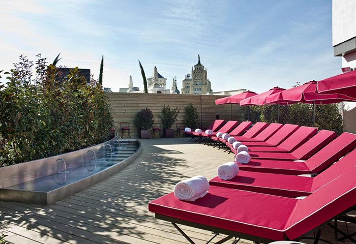 Rooftop bar at The Principal Madrid Hotel, a luxury gay hotel in Madrid. Cool rooftop restaurant, red sunbeds, and views of Madrid's skyline.