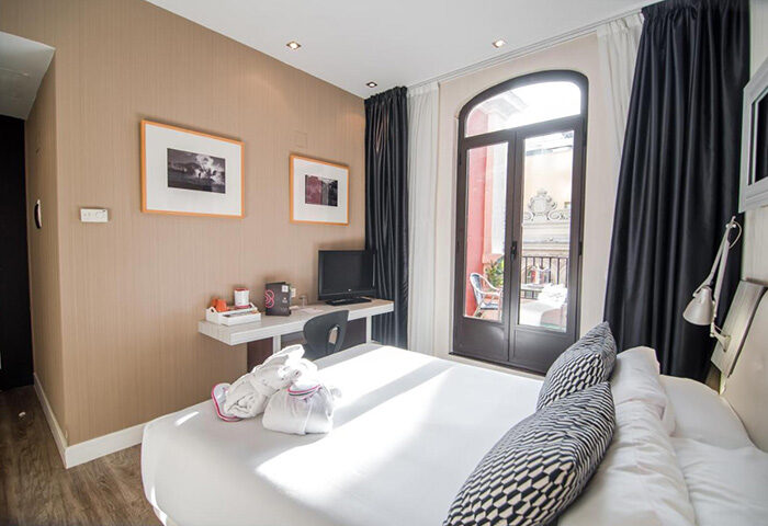 Petit Palace Chueca, Madrid gay hotel room. Balcony view, desk, and TV. Best party hotel in Madrid city center for gay travelers.