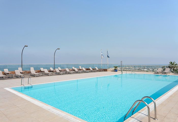 Sheraton Tel Aviv Hotel's rooftop pool. A luxury gay hotel with ocean views, lounge chairs, and clear blue water. Perfect for a gay travel getaway.