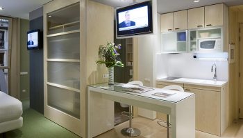 Ako Suites Hotel Barcelona serviced apartment: modern interior with kitchen, breakfast bar, and TV. Best gay hotel for travel advice.