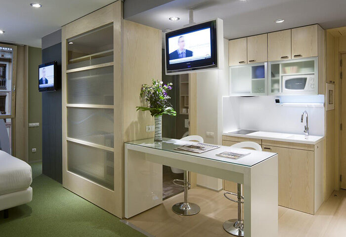 Ako Suites Hotel Barcelona serviced apartment: modern interior with kitchen, breakfast bar, and TV. Best gay hotel for travel advice.