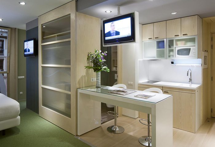 Ako Suites Hotel Barcelona serviced apartment: modern interior with kitchen, breakfast bar, and TV. Best gay hotel for travel advice.