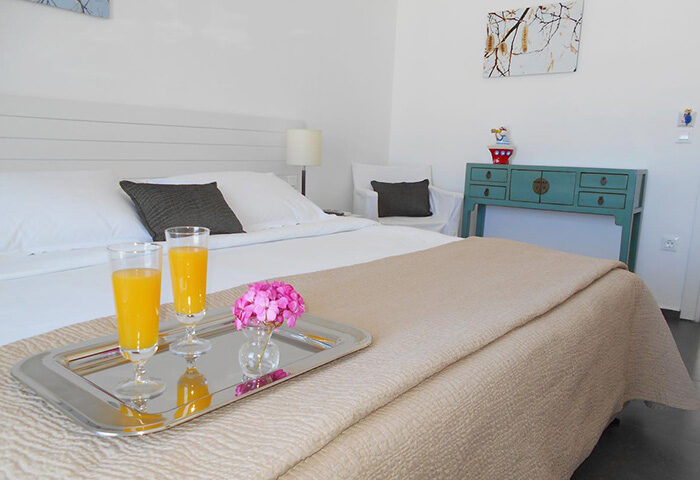 Portobello Boutique Hotel, Mykonos gay hotel. Room service with orange juice and flowers on a tray in a simple, basic room. Gayborhood travel.