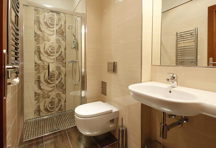 Anyday Apartments bathroom in Prague gayborhood. Shower with rose tile design, sink, and toilet. Budget gay hotels in Prague.