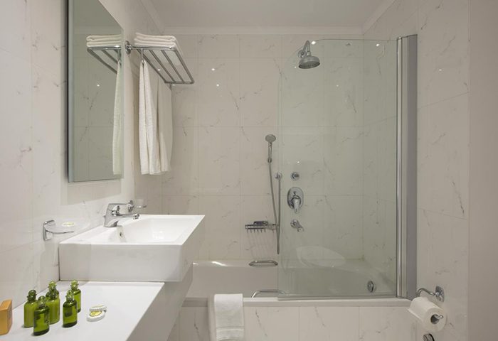 Despotiko Hotel bathroom. Modern, bright, and clean design. Bathtub with shower. Mykonos Town gay hotel, a cheap gay hotel in gayborhood.