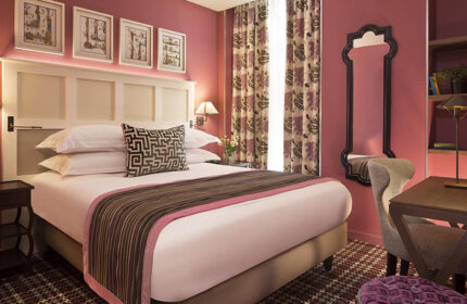 Les Tournelles, a gay hotel in Paris' Marais gayborhood. Room interior with bed, desk, mirror, and patterned accents. Cheap price, updated.