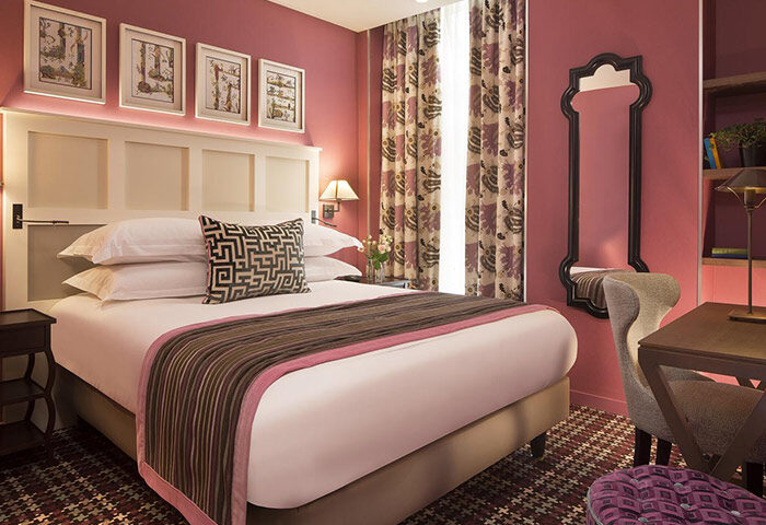 Les Tournelles, a gay hotel in Paris' Marais gayborhood. Room interior with bed, desk, mirror, and patterned accents. Cheap price, updated.
