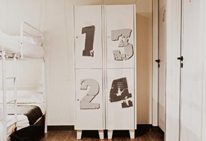 Room007 Chueca Hostel dorm room. Bunk beds, lockers with numbers, wood floor. Cool design gay hostel in Madrid city center gayborhood.