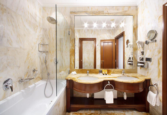NH Collection Carlo IV, Prague Old Town: Bathroom with marble walls, double sink, large mirror, bathtub with shower. Gay-friendly hotel.