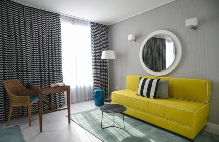Melody Hotel, an Atlas Boutique Hotel room. Gay hotel in Tel Aviv near Hilton Gay Beach. Modern decor with yellow couch and round mirror.