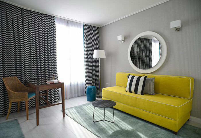 Melody Hotel, an Atlas Boutique Hotel room. Gay hotel in Tel Aviv near Hilton Gay Beach. Modern decor with yellow couch and round mirror.