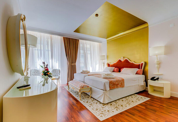 Hotel Borges Chiado room in Lisbon's gayborhood. Twin beds, gold accents, and elegant decor. Gay hotel for gay men travel in Lisbon.